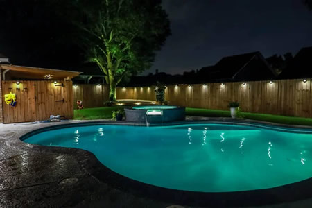 fence lights over looking a pool in Wilmington, DE lit by low voltage path lights at dusk
